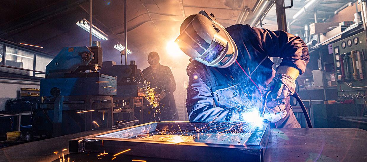 two handymen performing welding and grinding in the workshop